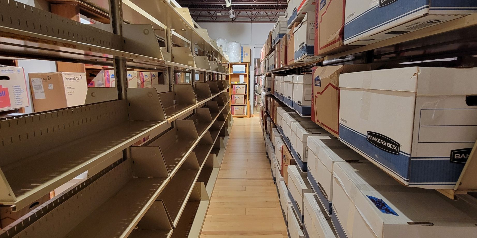 Empty library shelving beside carefully boxed books during a collection transition